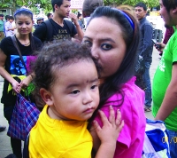 A Young Lady With Her Small Kid Waiting At Railway Station.